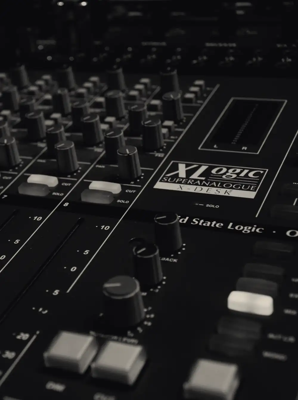 Mesa de mixagem analógica em close, com os faders e os botões de canal